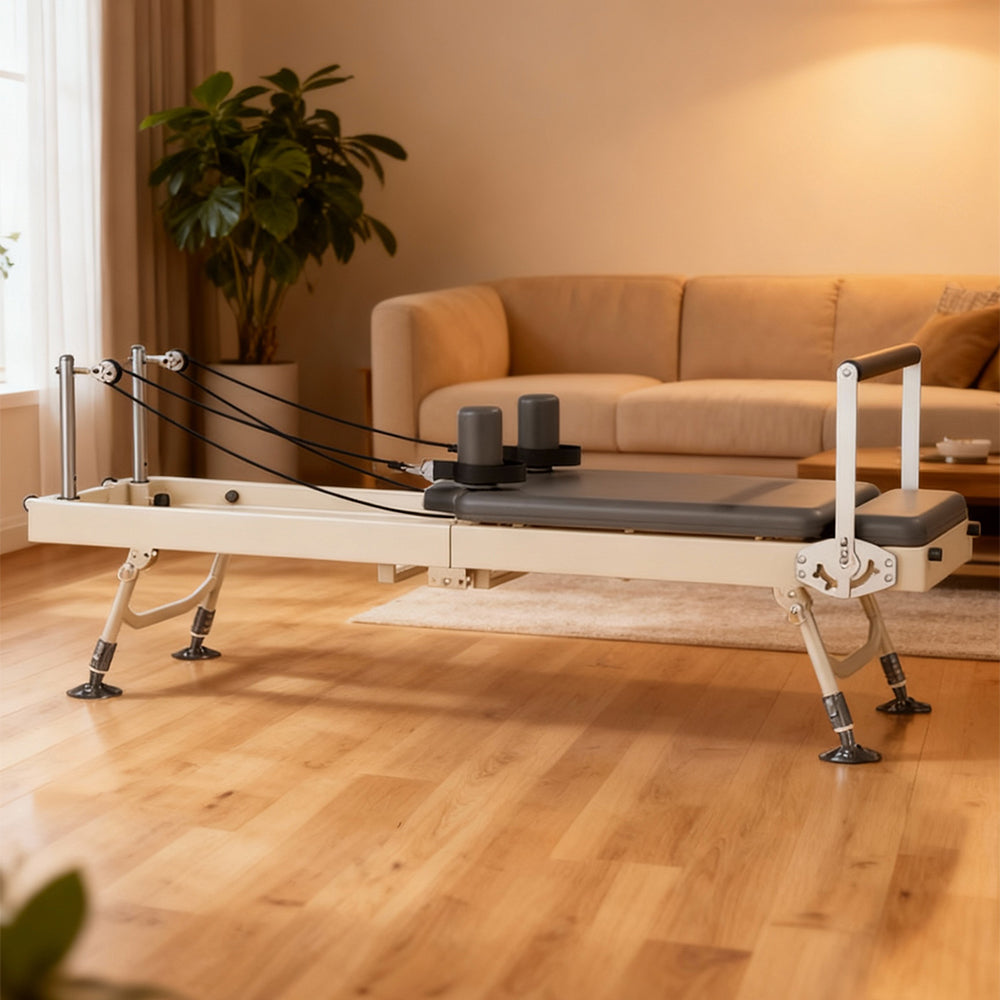Pilates reformer machine in a home setting with a couch and plant in the background